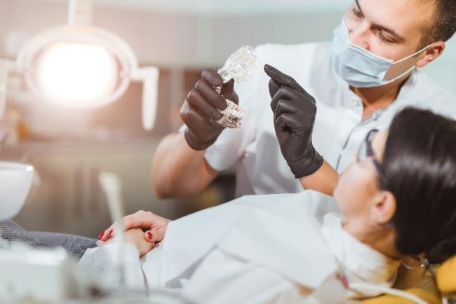 רופא שיניים מסביר למטופלת על כתרים לשיניים, במסגרת רפואת שיניים משמרת 